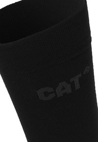 Chaussette en coton noir avec une texture côtelée, arborant un logo gris. Le design comprend un poignet renforcé pour plus de durabilité.