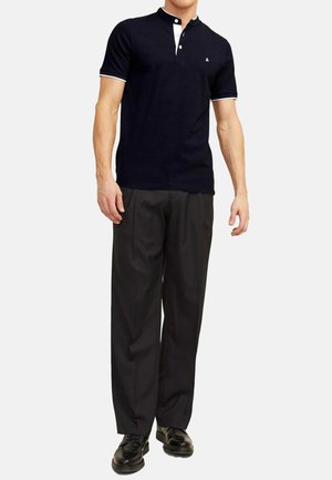 Polo shirt blu navy con colletto Henley, botttoni bianchi e rifiniture bianche a contrasto. Abbinato a pantaloni formali scuri e scarpe nere.