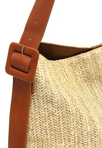 Gewebte Strohtasche mit strukturiertem Muster, ausgestattet mit einem breiten braunen Ledertragegurt und einem quadratischen Schnallen-Detail.