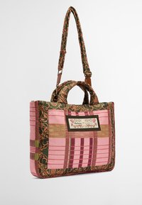 Gepatchte Tragetasche im pinken und grünen Karomuster, mit braunen Ledergriffen, floralen Akzenten und einem dekorativen Label-Patch.