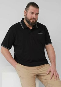 Schwarzes Polohemd mit grauem gestreiften Kragen und Bündchen, kurzen Ärmeln und seitlichen Schlitzen am Saum. Logo auf der Brust. Leichte Stoffstruktur.