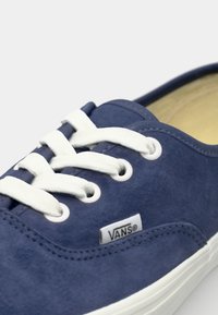 Navy blue suede sneaker with white laces and eyelets, featuring a white rubber sole and a small Vans logo tag on the side.