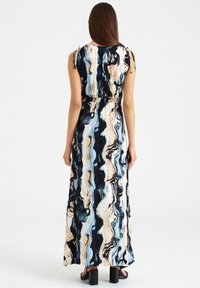 Maxi sukienka w abstrakcyjne, wirowane wzory w niebieskim, czarnym i beżowym kolorze, z regulowanymi sznurkami na ramionach i marszczoną talią dla podkreślenia kształtu.