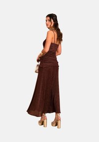 Braunes glitzerndes Maxikleid mit tailliertem Oberteil und fließendem Rock. Verfügt über dünne Träger und ein gerafftes Design. Kombiniert mit goldenen Blockabsatzsandalen.
