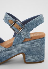 Blå denim plattform sandaler med bred stropp, justerbar spenne og brune skinnakenter. Myk inner såle med teksturert overflate.
