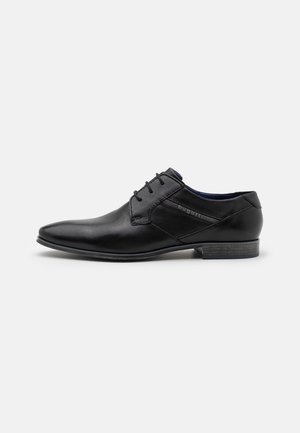 Chaussure formelle en cuir noir au design épuré, dotée d'un petit talon, d'une surface lisse et d'un branding subtil sur le côté.