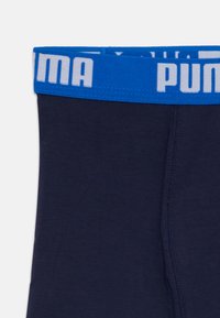 Marineblå boxershorts med en bred elastisk linning som har «PUMA» i hvite bokstaver. Glatt tekstur og tettsittende design.
