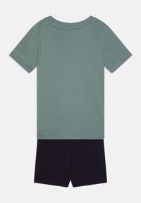 T-shirt a maniche corte in morbido tessuto verde abbinato a pantaloni corti blu scuro, con un design semplice senza motivi o dettagli.