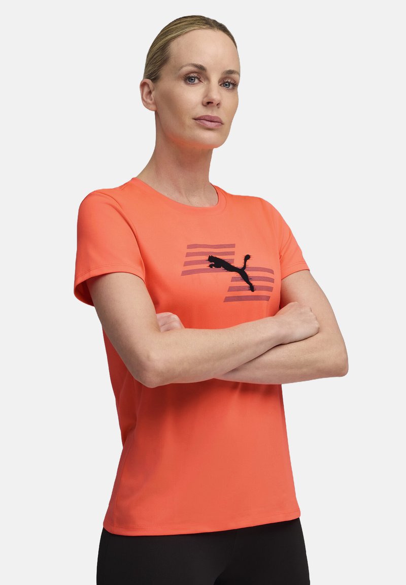 Bright orange short-sleeve T-shirt made of soft fabric, featuring a black Puma logo over diagonal stripes. Round neckline and relaxed fit.