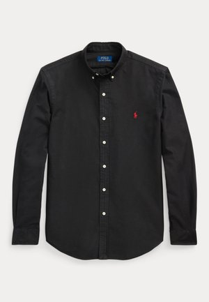 Camisa de algodão preta com botão, com colarinho pontudo, botões brancos e um logótipo bordado em vermelho no lado esquerdo do peito. Corte ajustado.