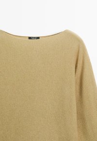 Beżowy sweter dzianinowy z szerokim okrągłym dekoltem i czarną metką z napisem "Massimo Dutti" na tylnym kołnierzu.