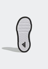 Podešev bot Adidas, která má bílý hexagonální vzor s černými akcenty. Texturovaný povrch pro lepší přilnavost. Logo umístěné blízko paty.