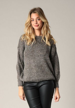 Pull en tricot gris avec texture côtelée, col rond et manches ballon. Associé à un pantalon en cuir noir pour un look décontracté.