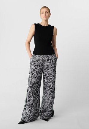 Black ribbed sleeveless top paired with wide gray leopard print trousers featuring side stripes and pockets, worn with pointy black heels.