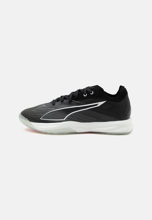 Chaussure de sport basse noire avec semelle blanche et un élégant logo blanc sur le côté, vue de la face externe sur un fond uni.