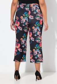 Zwarte cropped broek met bloemenprint in verschillende kleuren. Zacht materiaal, elastiche tailleband en een flared design. Gecombineerd met zwarte hakken.