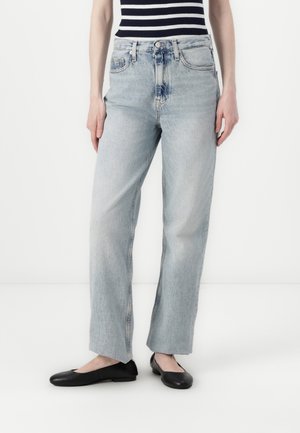 Light blue, high-waisted jeans with a straight leg, faded finish, and slight fraying at the hem, paired with black flat shoes.
