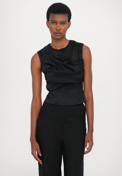 Black sleeveless top with draped fabric detail, smooth texture, and fitted silhouette, paired with high-waisted black trousers.