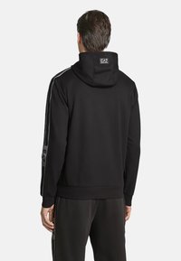 Felpa nera con cappuccio regolabile, orlo a coste e strisce laterali con logo. Realizzata in tessuto morbido, ha una vestibilità comoda.