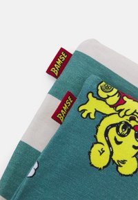 Dois itens de tecido empilhados, um em tom de teal com uma ilustração de um urso amarelo, o outro em creme com riscas teal, cada um com uma etiqueta vermelha "Bamse".