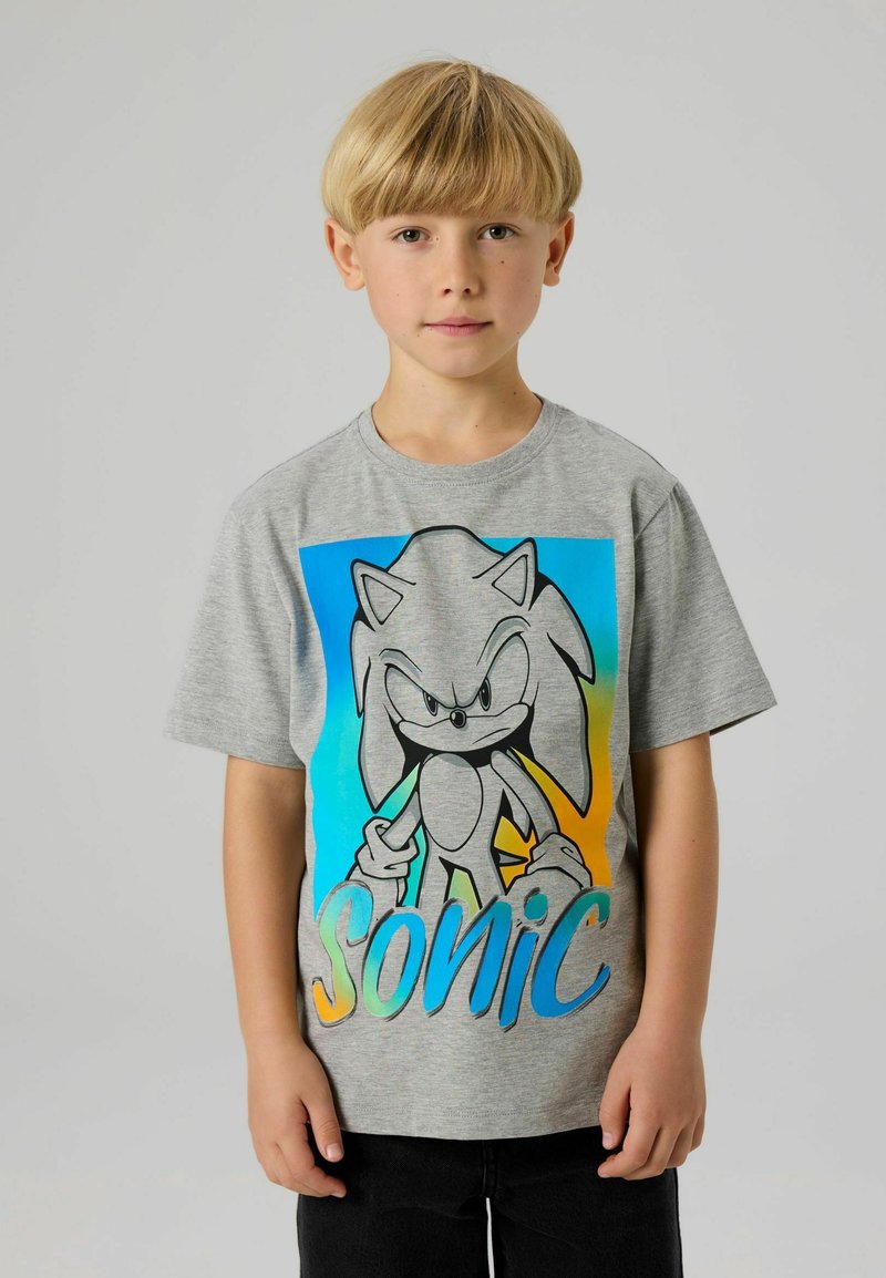 Szara bawełniana koszulka z dużą grafiką Sonic w czerni i niebieskim, z napisem „Sonic” w gradiencie niebieskiego i zielonego. Krótkie rękawy.