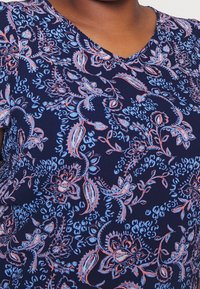 Top di tessuto blu navy con scollatura a V, decorato con un motivo floreale paisley in azzurro chiaro e corallo. Texture morbida con maniche corte.