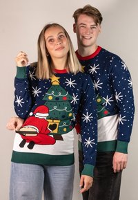 Strickweihnachtspullover mit blauem Hintergrund, rotem Kragen, grünen Akzenten, Weihnachtsbaum und einem verspielten Weihnachtsmann-Design auf der Vorderseite.