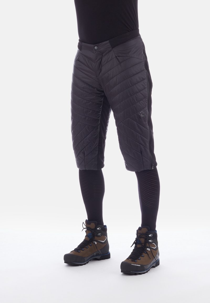Shorts neri trapuntati con un design strutturato, caratterizzati da gambe affusolate e tasche laterali, abbinati a leggings neri e scarponi da trekking marroni.