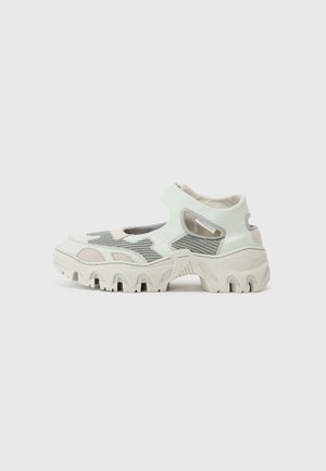 Zapatillas de deporte en verde menta claro y gris con superposiciones de malla, suela blanca gruesa y cuello acolchado. Diseño distintivo y voluminoso con detalles recortados.