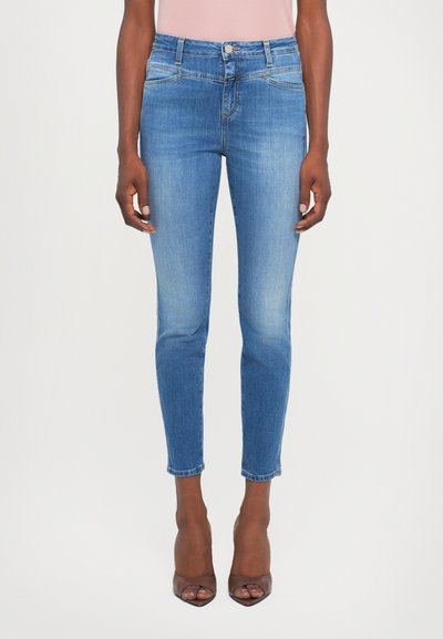 Jeans skinny en denim bleu avec une taille mi-haute, dotés de poches avant et d'un léger dégradé. Courts au niveau de la cheville avec un ourlet net.