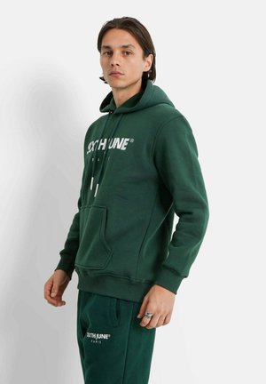 Hoodie vert avec une poche avant, cordons de serrage ajustables et un logo blanc ; associé à un pantalon de survêtement assorti arborant le même logo.