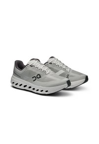 Baskets de sport gris clair avec tige en mesh et accents noirs. Semelle arrondie avec trous de ventilation et lacets plats pour un maintien sécurisé.