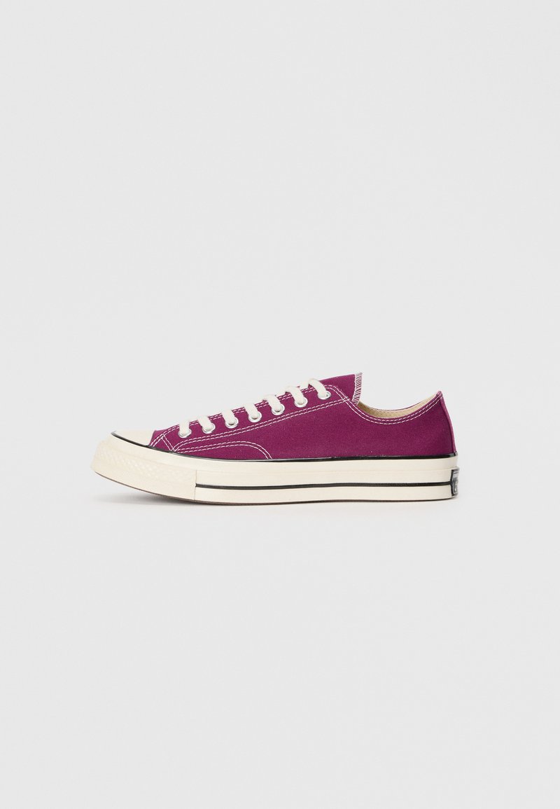 Purple canvas sneaker with a low-top design, white rubber sole, and black trim. Features six eyelets and contrasting stitching details.