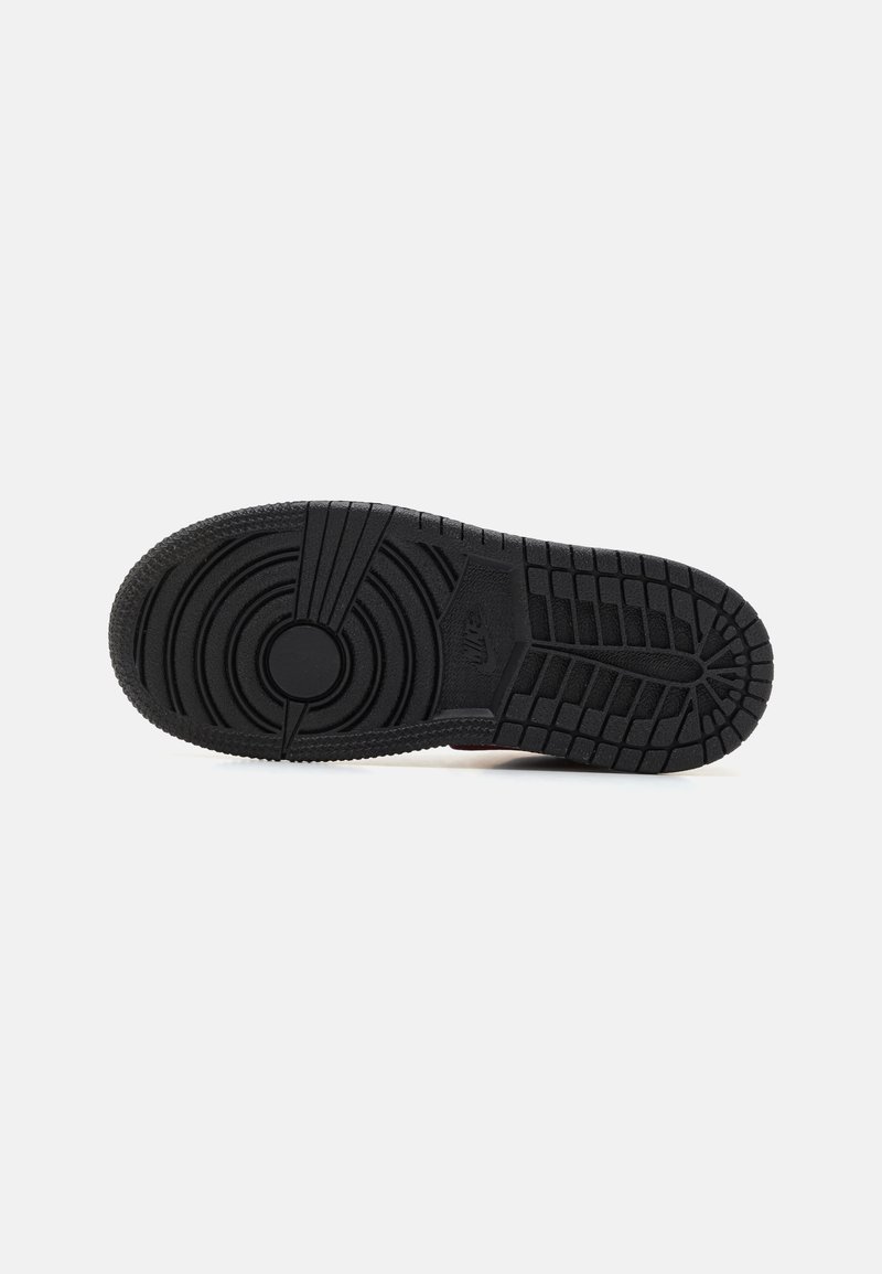 Semelle de sneaker en caoutchouc noir avec un motif texturé, détail de logo circulaire, cercles concentriques et un design de semelle en grille pour l'adhérence.