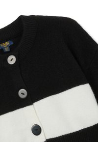 Cardigan noir avec une rayure horizontale blanche, présentant une texture côtelée. Inclut trois boutons de tailles et de couleurs variées.