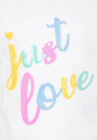 Un tissu blanc présente un design de texte coloré, "just love", en sequins jaunes, roses, bleus et verts, avec un petit accent de cœur en jaune.