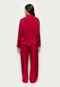 Roter Satin-Pyjama-Set mit einem knöpfbaren Langarmoberteil, das vertikale Streifen aufweist, und weitem Hosen mit kontrastierenden Bündchen.