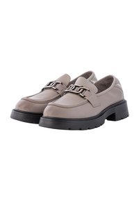 Beige leather slip-on shoes with black chunky soles, featuring a decorative metal chain accent and smooth, rounded toe design.