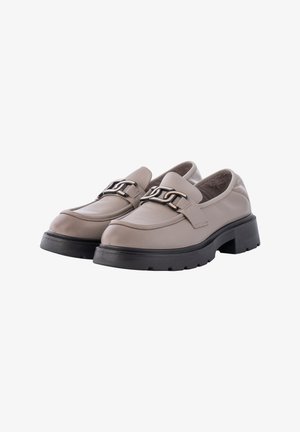 Beige Leder Slipper mit schwarzen klobigen Sohlen, die mit einem dekorativen Metallkettenakzent und einem glatten, runden Zehendesign versehen sind.