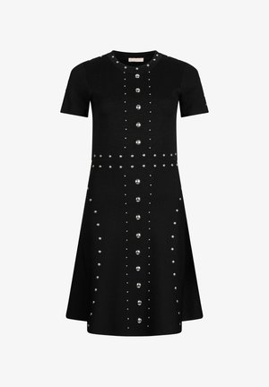 Czarna dzianinowa sukienka z krótkimi rękawami, ozdobiona srebrnymi ćwiekami ułożonymi w pionowe linie, z rozkloszowanym dołem.