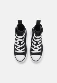 Czarne sneakersy za kostkę z białymi gumowymi podeszwami i czubkami. Posiadają białe sznurówki oraz pętelkę na pięcie dla łatwego zakupu.
