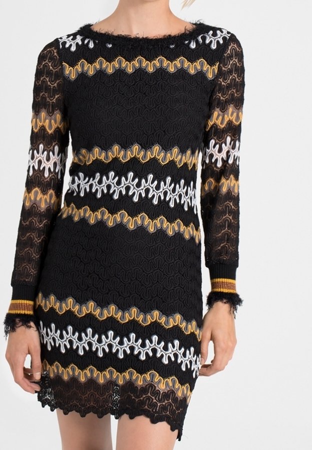 Svart spetsklänning med långa ärmar, vågiga mönster i vitt, gult och orange, med texturerad frans vid fållen och ärmsluten.