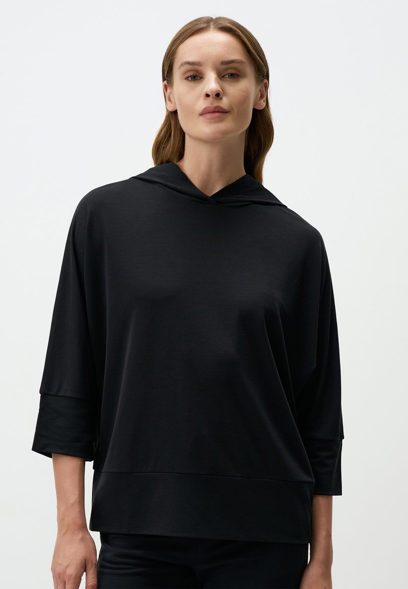 Felpa nera con vestibilità ampia, dotata di cappuccio, maniche a tre quarti e una trama liscia. Design minimalista, senza motivi o accenti visibili.