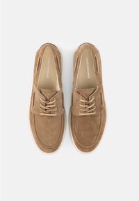 Ζευγάρι ταμπά γκρίζων παπουτσιών δετών boat shoes με λευκές σόλες, φωτογραφία από πάνω, σε ανοιχτό γκρι φόντο.