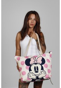 Canvas draagtas met een groot Minnie Mouse ontwerp, roze stippen en een touwhandvat. Verzorgd met een rits en kettingdetail.