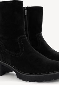 Botines de ante negros con textura suave, tacón bajo tipo bloque y cremallera lateral. Presentan costuras en contraste y suela robusta.