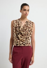 Mouwloze top met luipaardprint en een gedrapeerde kraaglijn; gemaakt van zachte stof, met tinten beige, bruin en donkere vlekken.