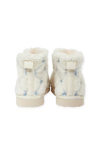 Flauschige cremefarbene Ankle Boots mit blauen Nähten. Sie verfügen über ein weiches, strukturiertes Äußeres und eine robuste, hellfarbige Sohle. Mit einem Hinterzieh-Band ausgestattet.