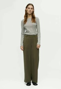 Gray long-sleeve top paired with high-waisted olive green wide-leg trousers and black footwear. Smooth fabric with minimal detailing.