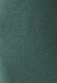 Zeleni rebrasti materijal s uspravnim prugama, koji ima mekanu teksturu. Materijal ima blago plišanu pojavu i uniformni uzorak.